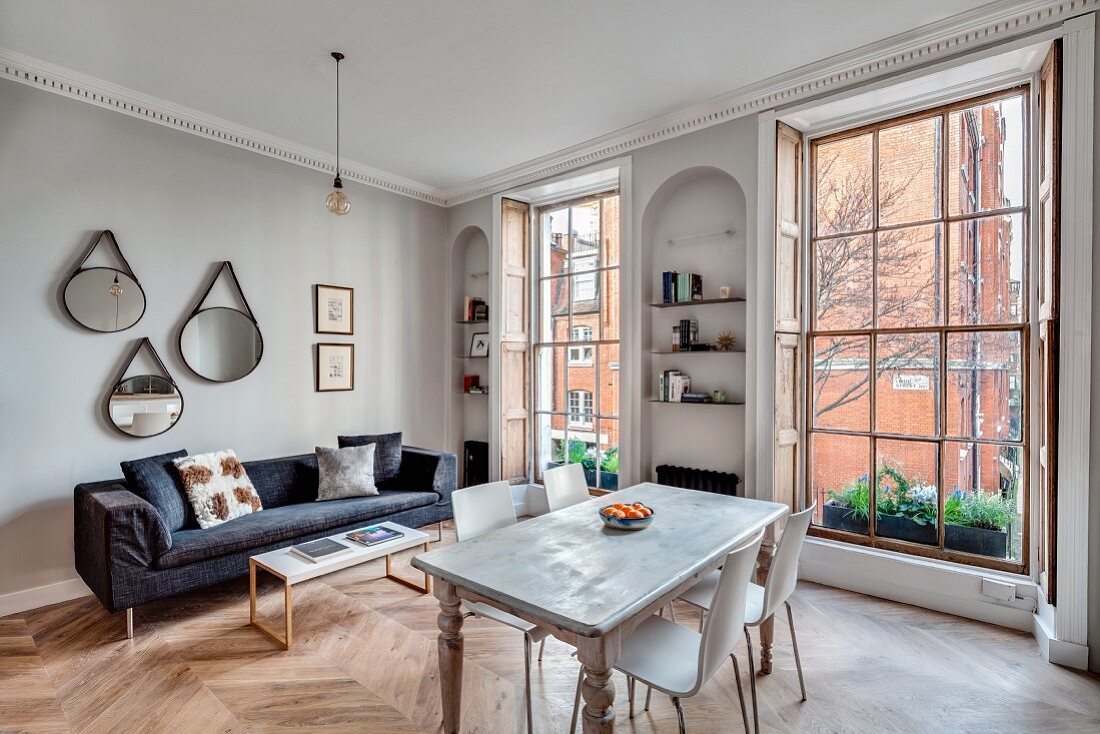 Dining table and sofa in open-plan interior of renovated townhouse apartment