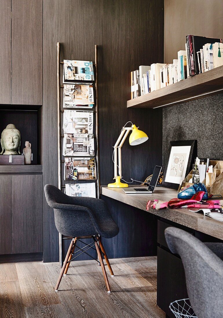 Dunkles Büro mit verkleideter Wand und gelber Schreibtischlampe