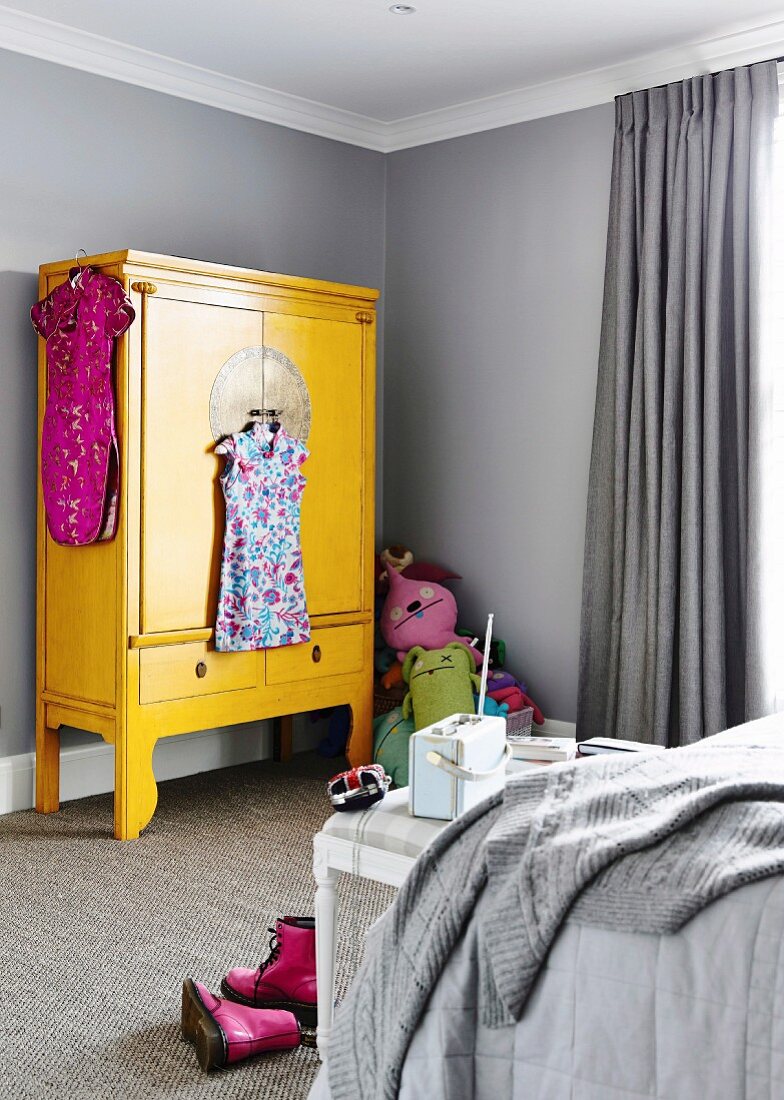 Gelber, asiatischer Kleiderschrank in grauem Kinderzimmer