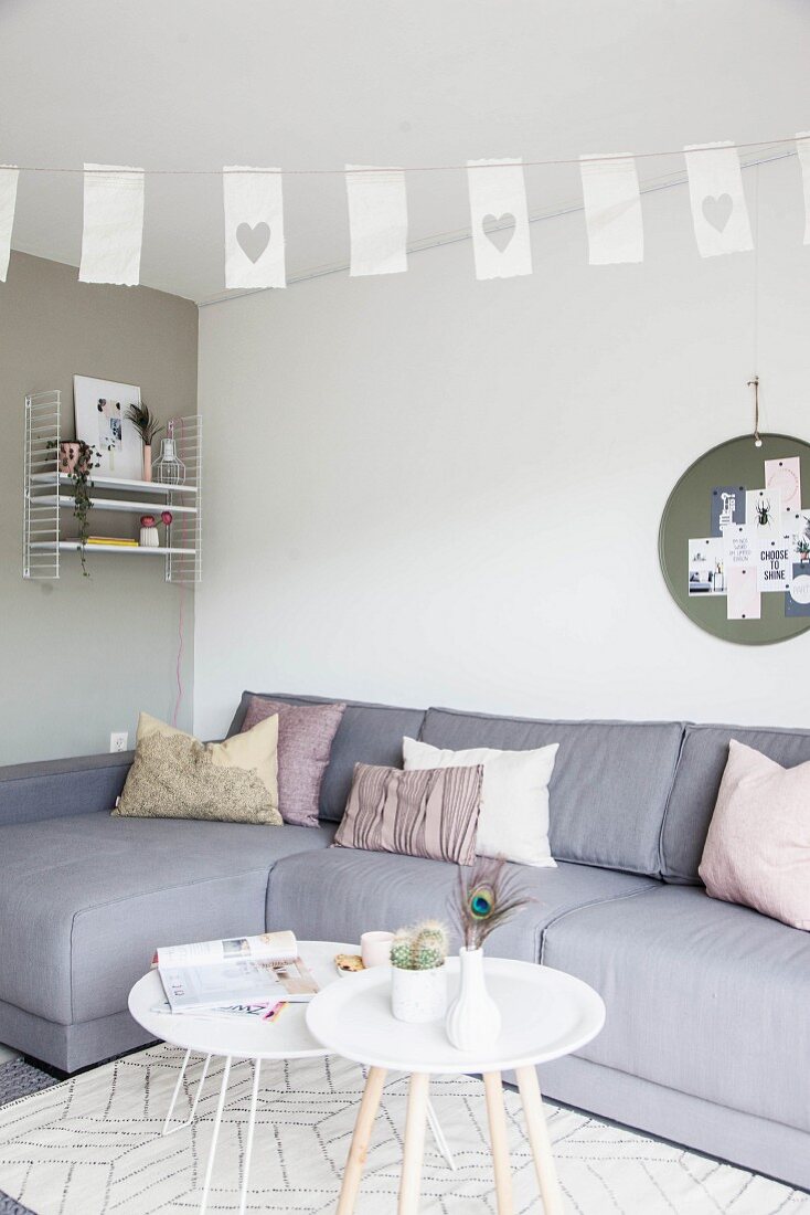 Grey corner sofa and white tray table in Scandinavian-style living room