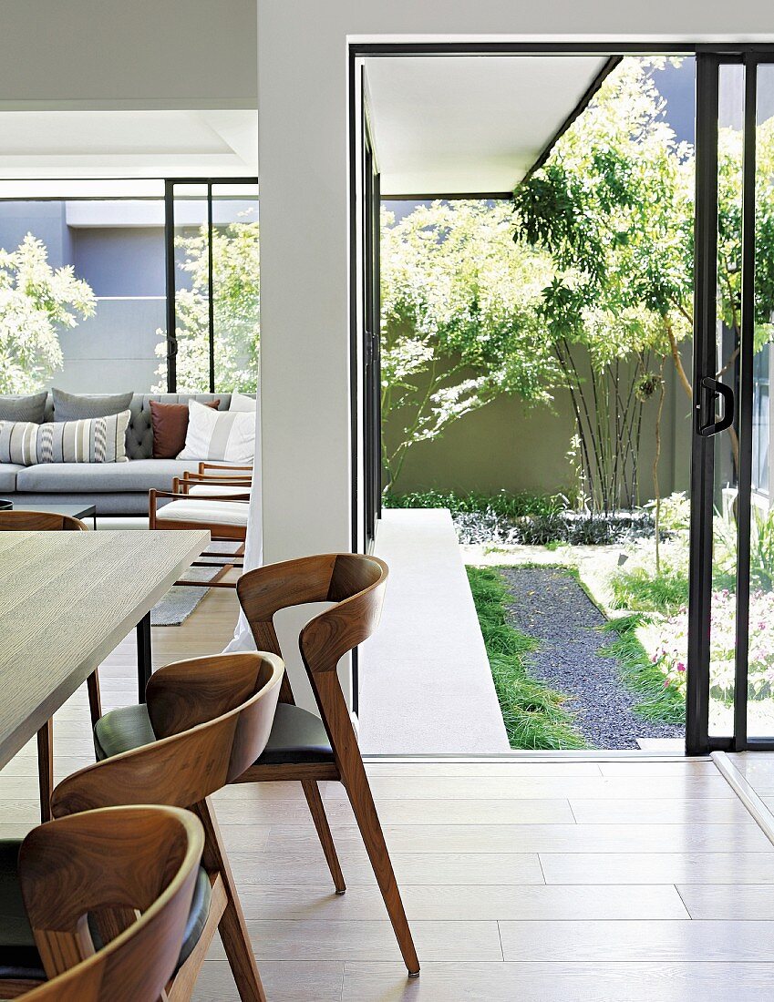 Moderne Holzstühle vor offener Terrassentür zum Garten