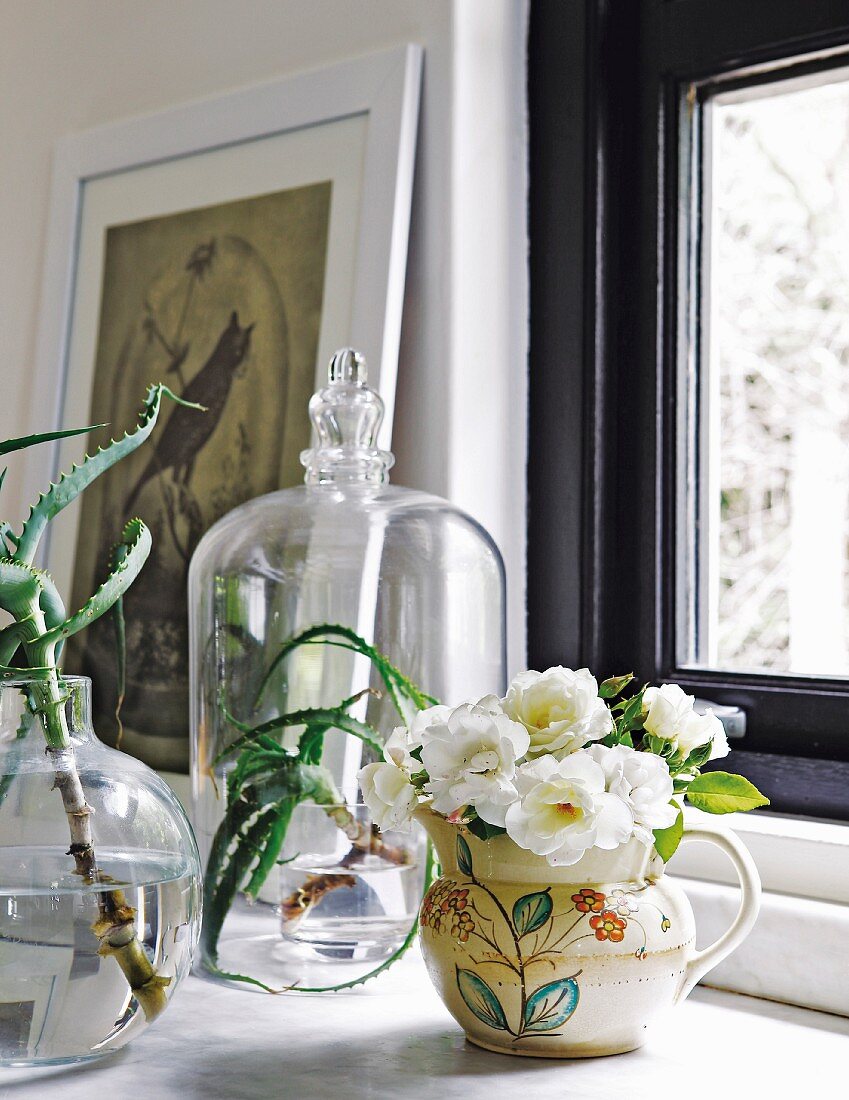 Blumen und Sukkulenten in Vasen und unter einer Glasglocke
