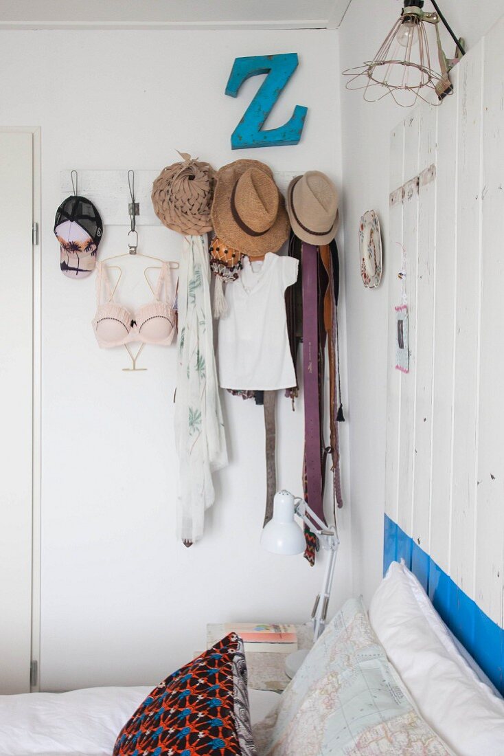 Vintage Kleiderhakenleiste mit verschiedenen Kleidungsstücken und Hüten in Schlafzimmer