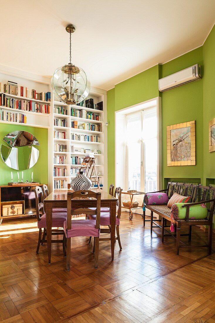 Floor to ceiling shelves and green walls in living room of period apartment