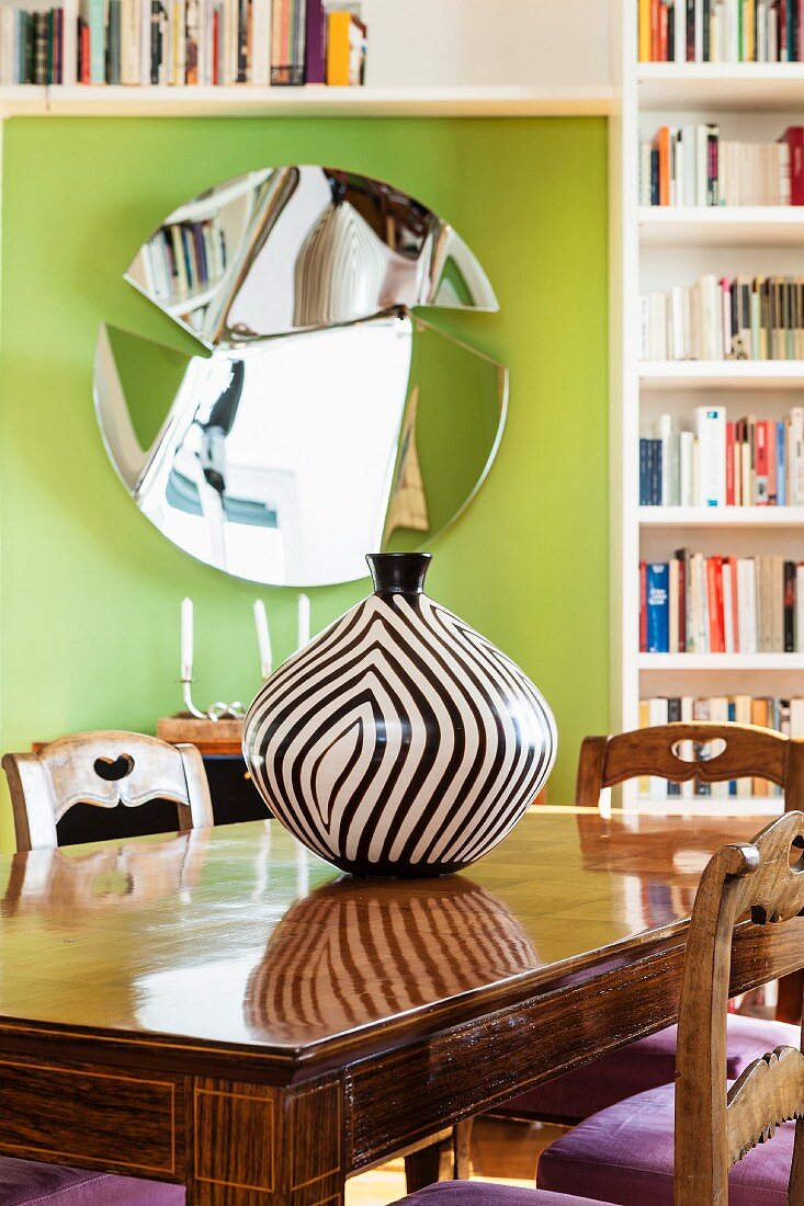 Schwarz-weiß gestreifte Vase auf einem Holztisch vor einem Spiegel