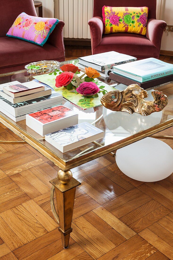 Books on glass-topped coffee table with gilt frame