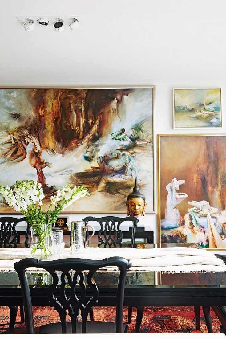 Dining table in front of large paintings on wall