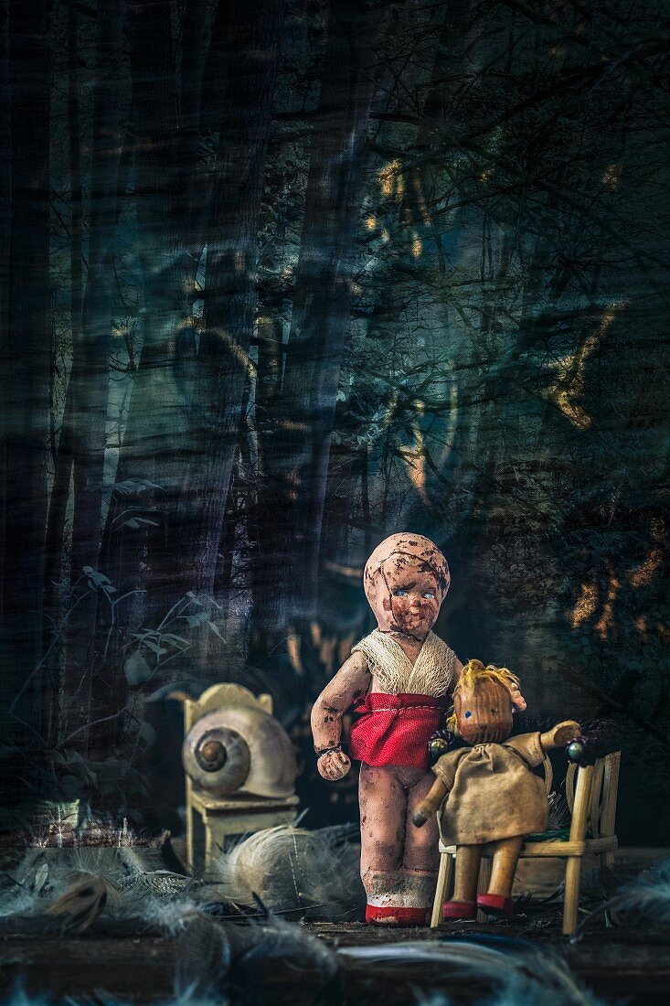 Morbide Miniatur-Puppen vor düsterem Hintergrund mit Puppenmöbel und Federn arrangiert