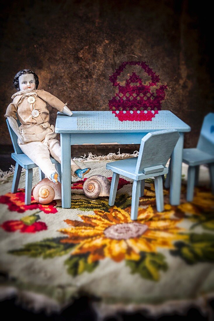 Pale blue dolls' furniture and macabre, antique male china doll on embroidered blanket