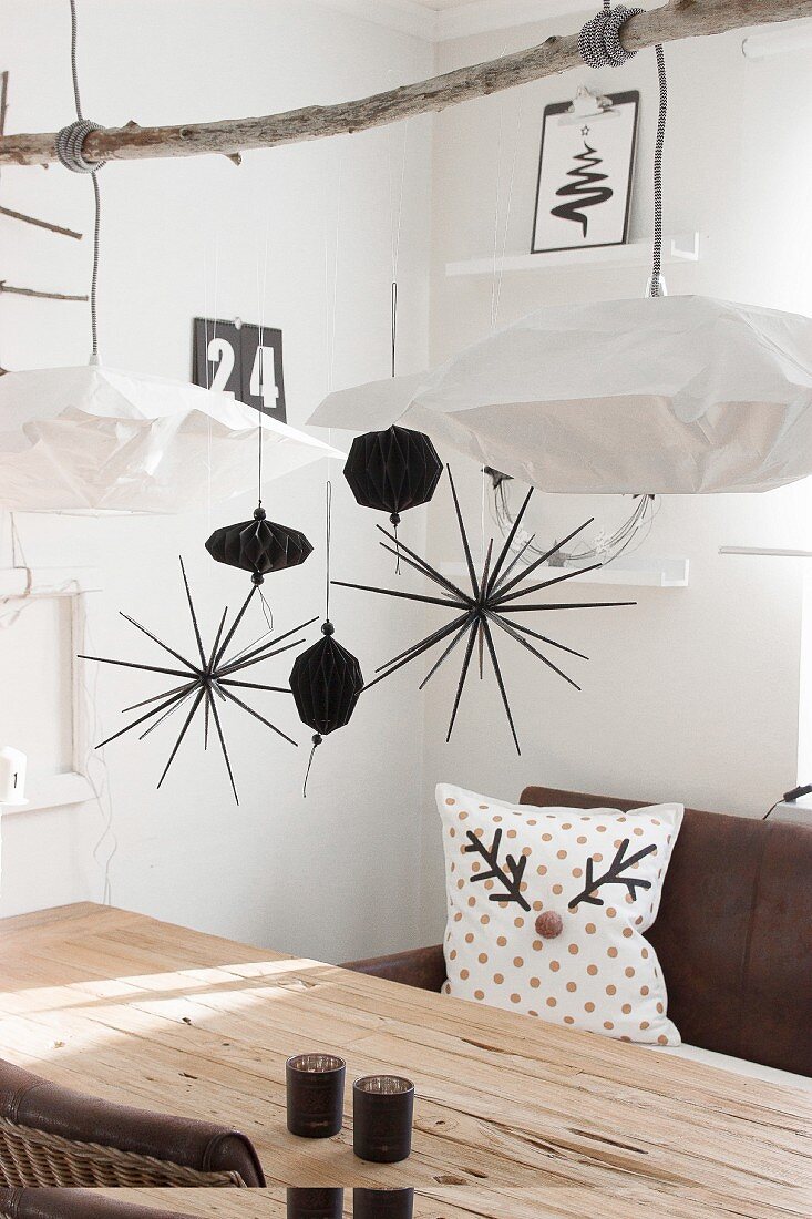 Black and white Christmas decorations hung from branch above dining table