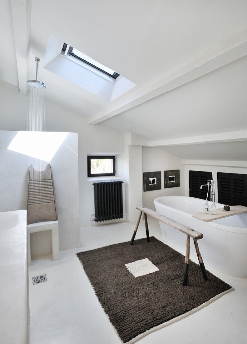 Bad im Dachgeschoss mit Dachflächenfenster, Duschbereich und freistehender weißer Badewanne