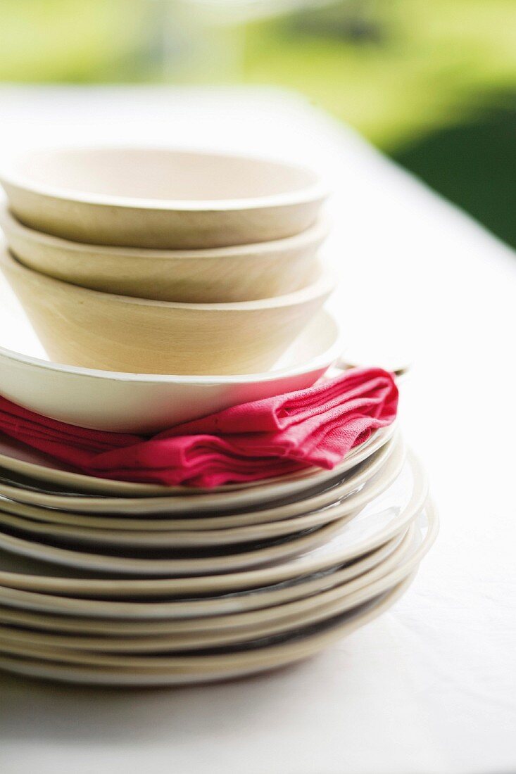 Stack of plates, bowls and napkins on garden table