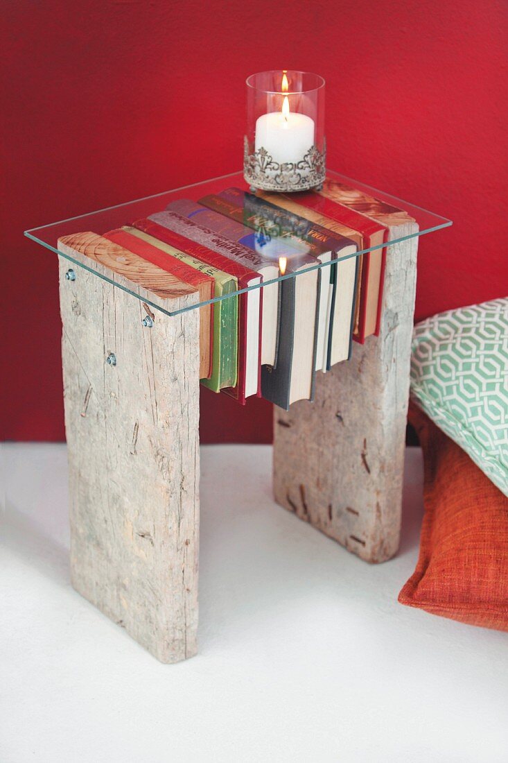 DIY-Beistelltisch aus zwei rustikalen Holzbrettern, durchbohrten Büchern und Glasplatte