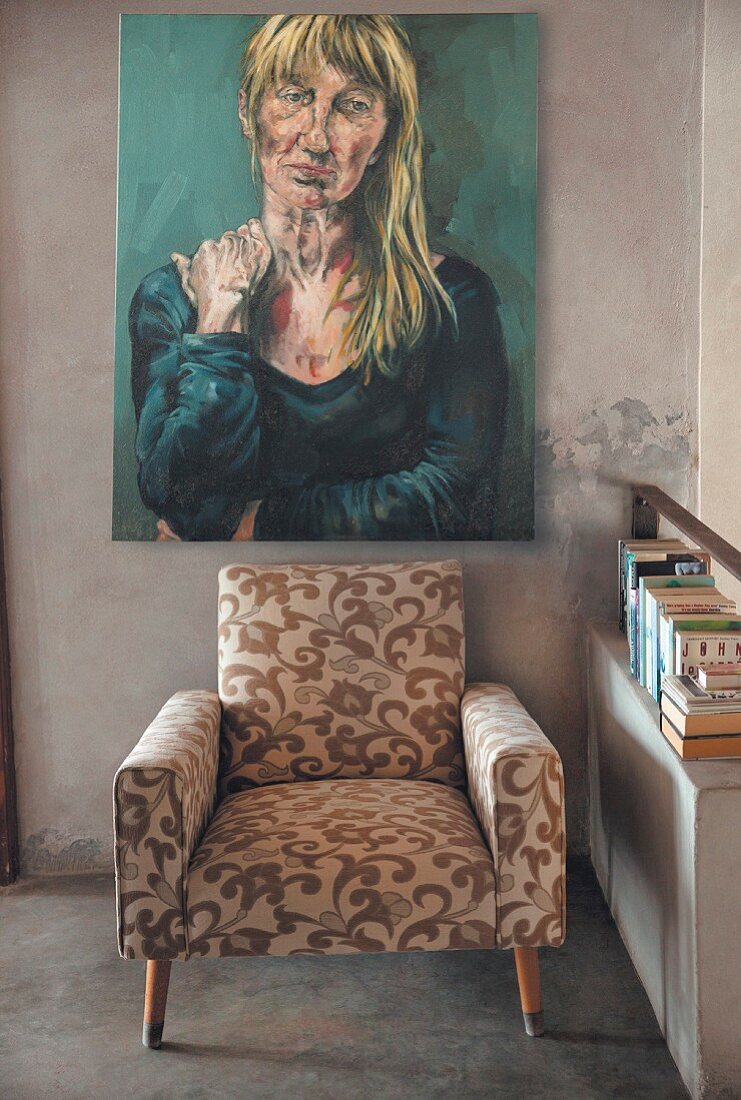 Portrait of woman above floral armchair next to shelf of books
