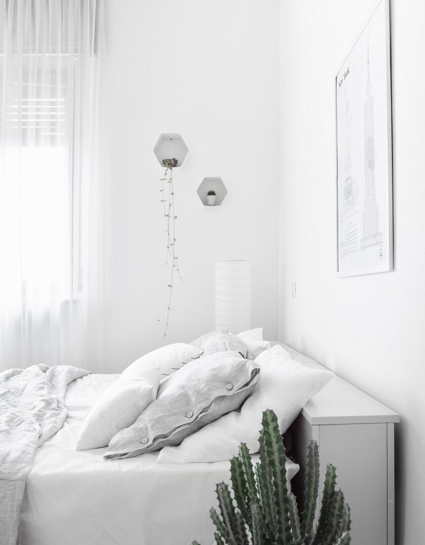 Weißes Schlafzimmer mit Stauraum am Kopfende des Bettes