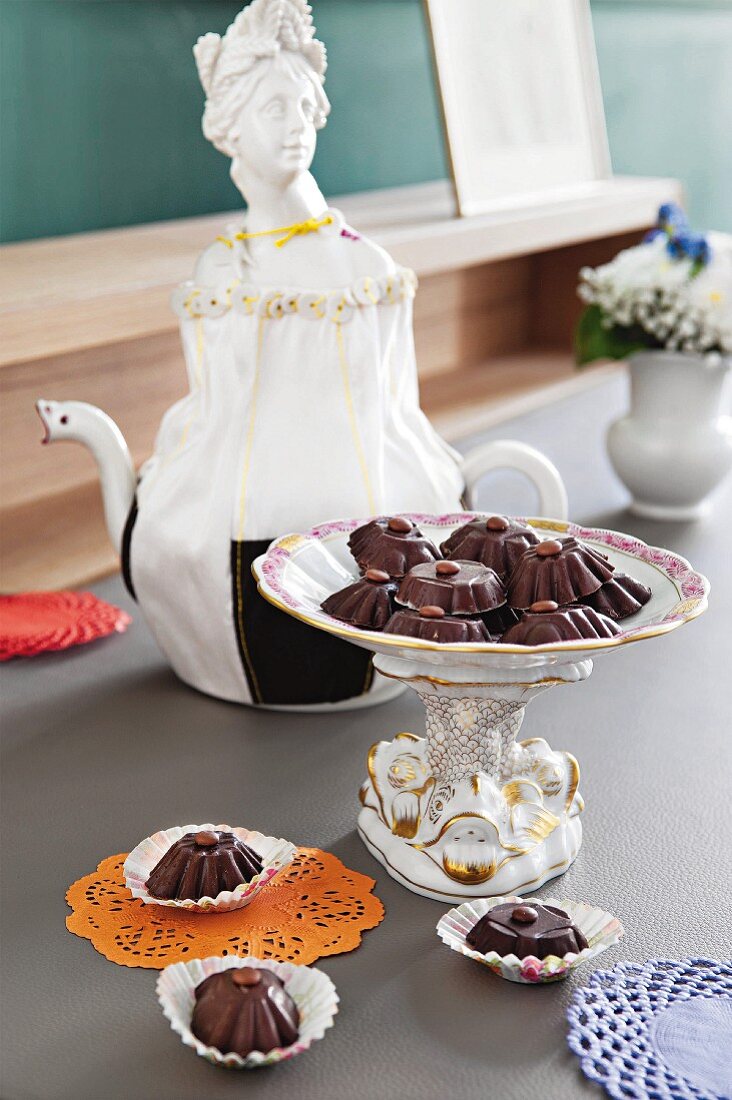 An elegant porcelain serving dish with home-made chocolate pralines in front of a nostalgic porcelain jug