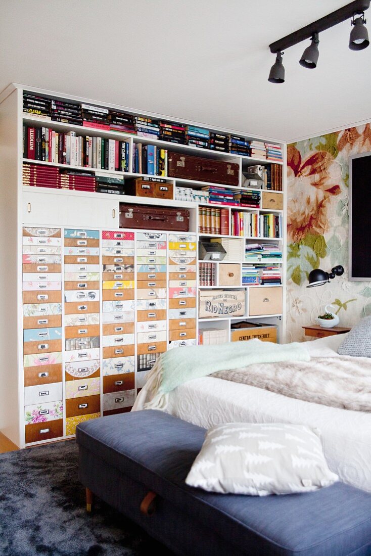 Regalwand mit verschiedenen, kreativ gestalteten Schubladen und vollen Regalfächern in Schlafzimmer