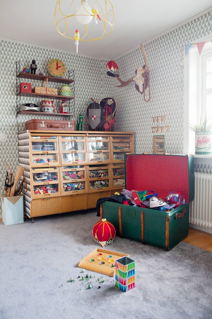 Sortiertes Spielzeug in Retro Schrank mit durchsichtigen Schubladen in Jungenzimmer