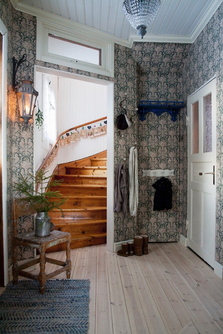 Patterned wallpaper, wooden floor and home-made Advent calendar on handrail of stair in traditional hallway