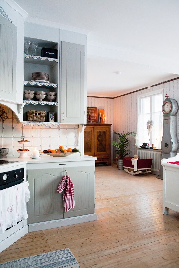 Landhausküche mit Blick in Wohnbereich mit Wiege und traditioneller Standuhr