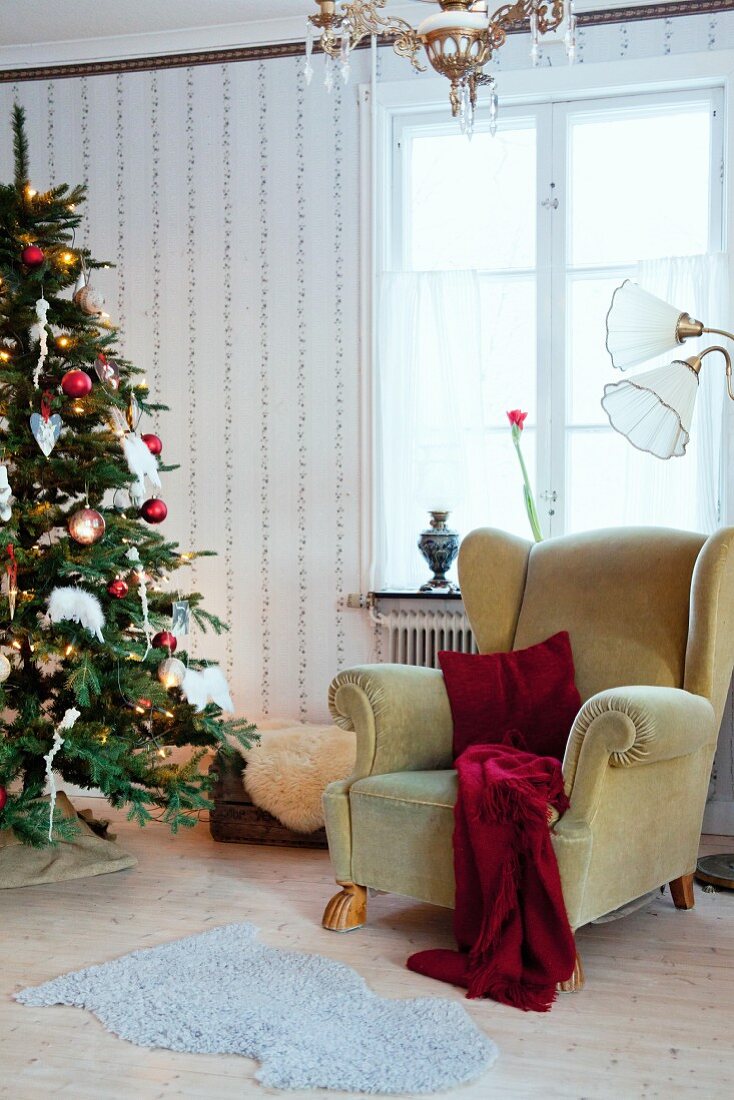 Gemütlicher Ohrensessel neben Weihnachtsbaum mit nostalgischem Flair