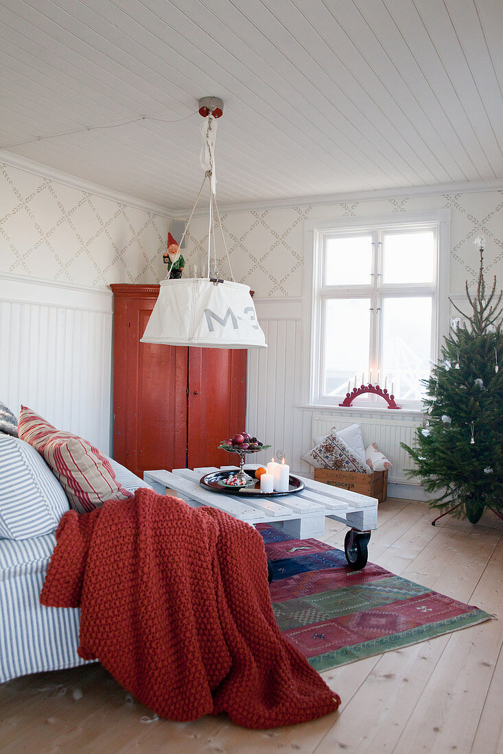 Skandinavisches Wohnzimmer mit Christbaum und roten Akzenten