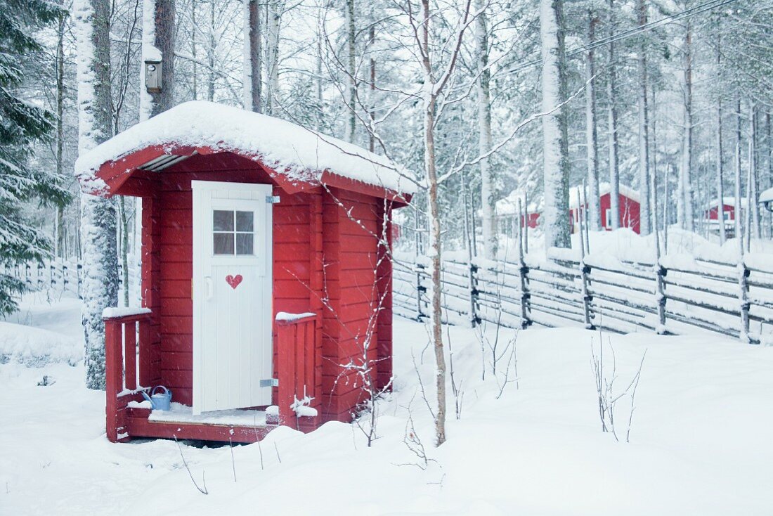 Small red wooden cabin in snowy woods