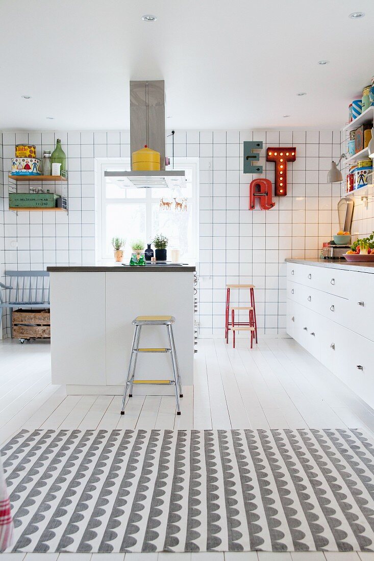 White fitted kitchen with colourful splashes of colour, island counter and creative ambiance