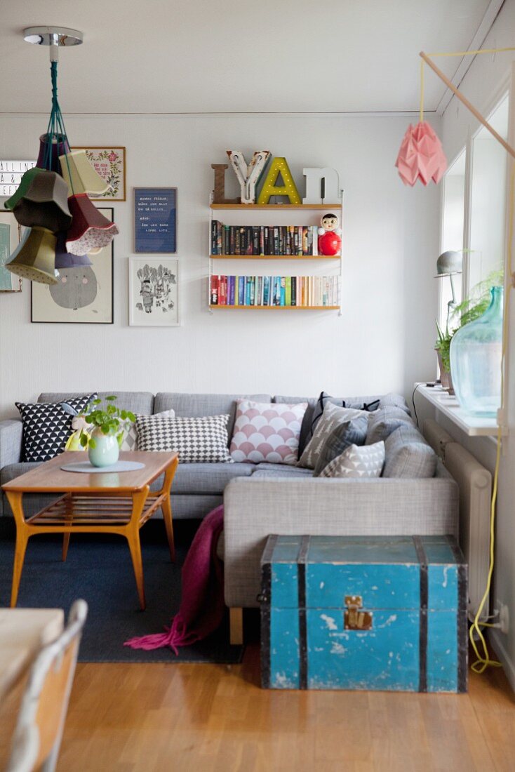 Gemütliche Wohnzimmerecke mit grauer Couch, String-Regal und Retroflair