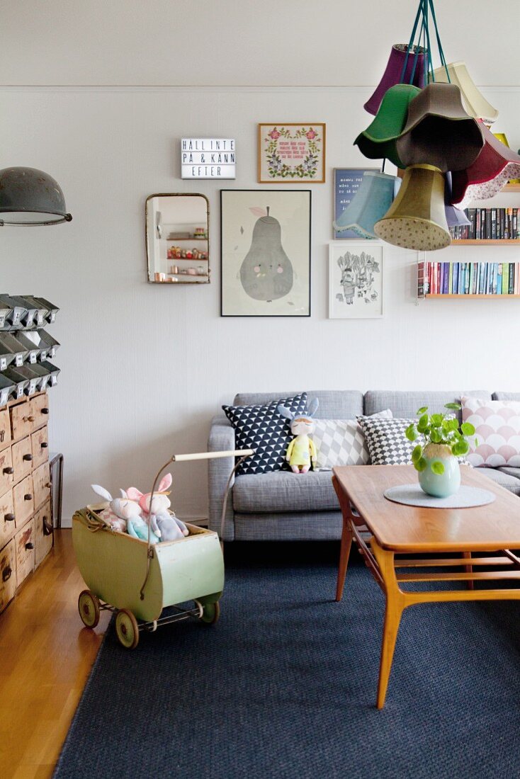 Gemütliches Wohnzimmer mit grauer Couch, Vintage Puppenwagen und Retroflair