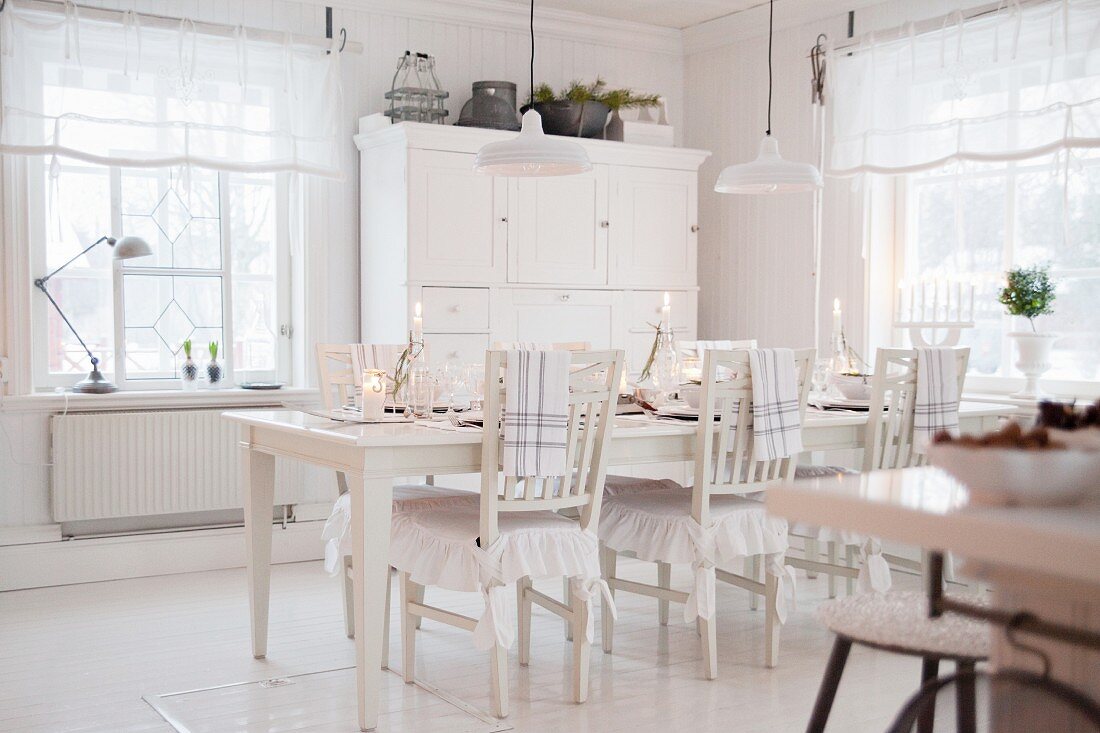 Festively set table in white country-house kitchen