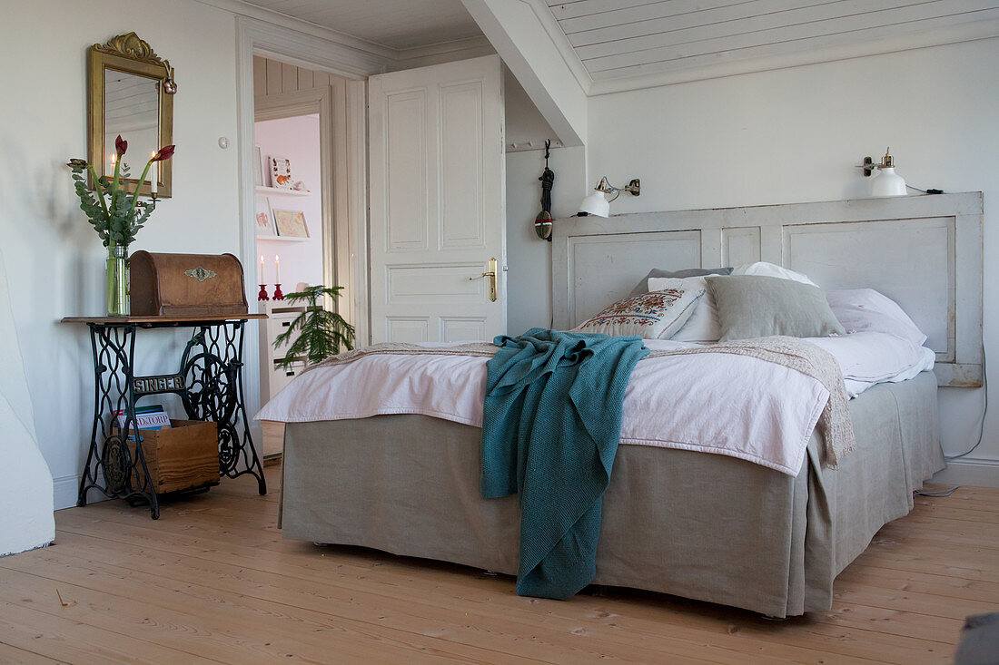 Bed with loose-covered frame and door used as headboard in bedroom