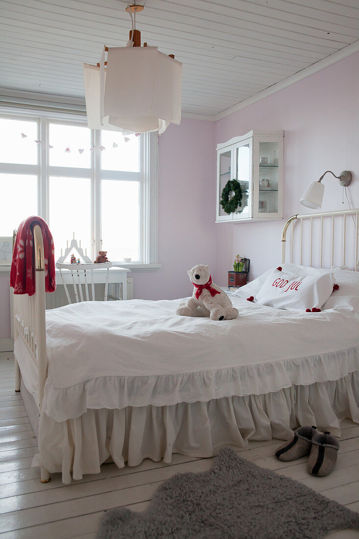 Metallbett mit Husse und Rüschen im Kinderzimmer mit rosa Wänden