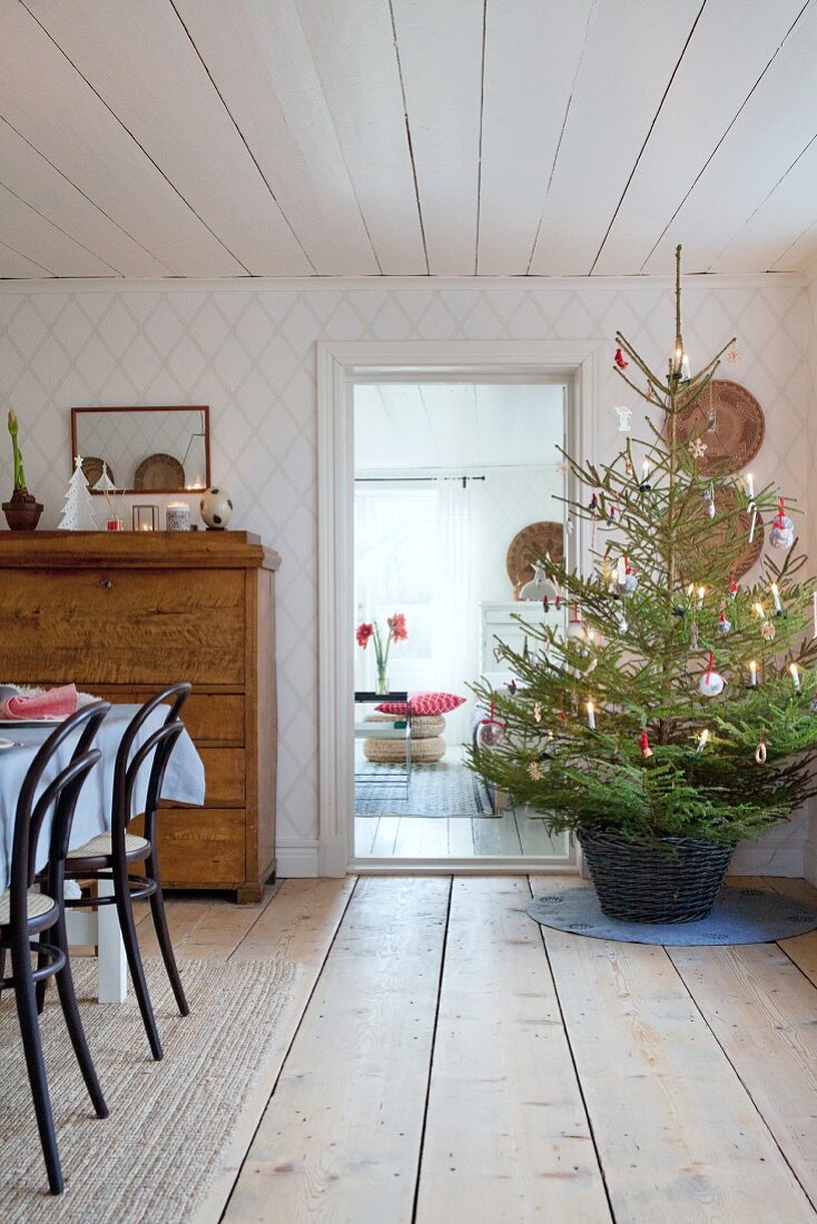 Decorated Christmas tree in basket in low-ceilinged interior