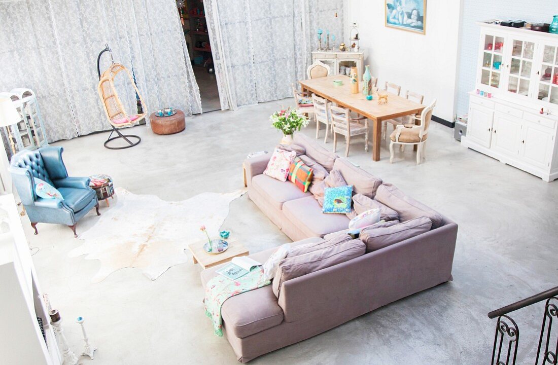Blick von Galerie auf gemütlichen Lounge- und Essbereich mit grauem Betonboden