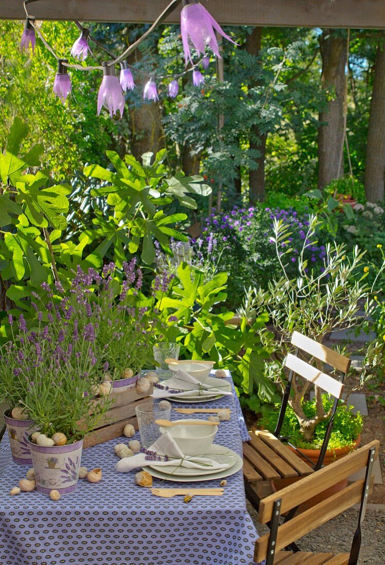 Gedeckter Gartentisch mit Lavendel und Schneckengehäuse dekoriert