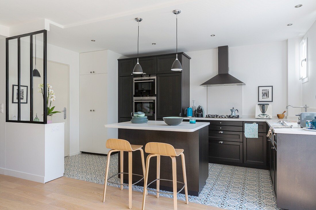 Black fitted kitchen with white worksurface in bright apartment