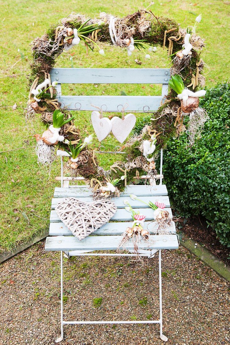 Herzförmiger Kranz mit Zwiebelblumen auf Gartenstuhl