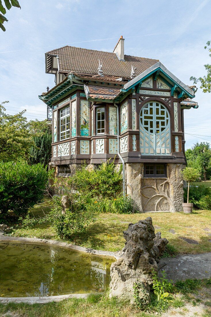 Traditionelles Fachwerkhaus mit asiatischen Stilelementen in sommerlichem Garten mit Teich
