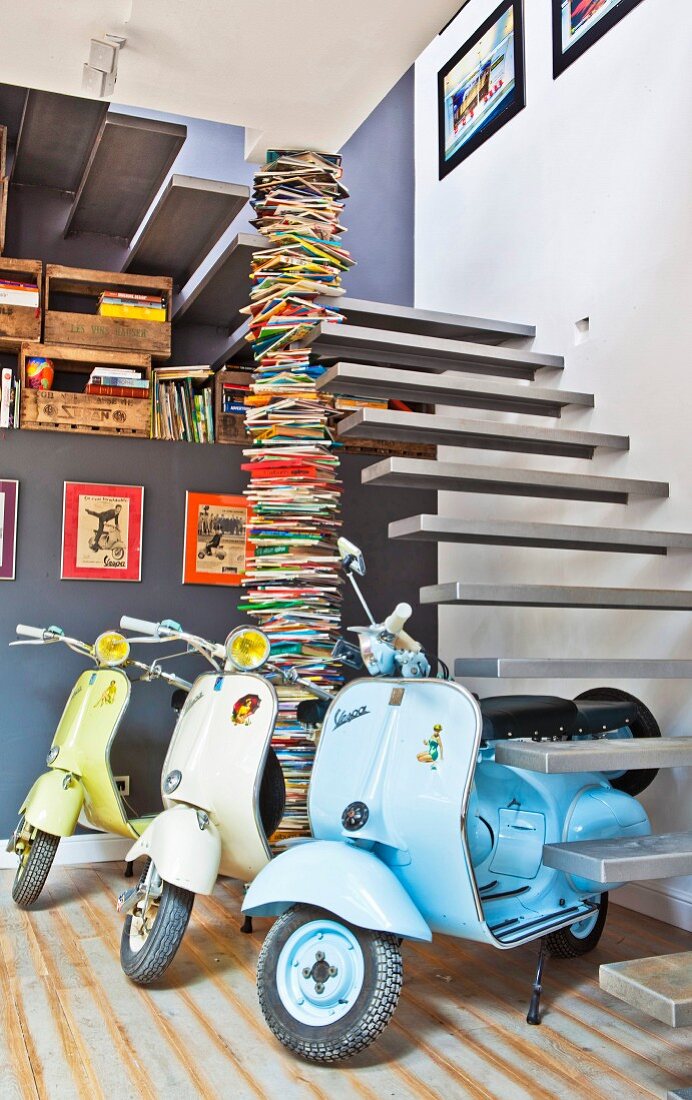 Three scooters at foot of floating staircase leading to living room
