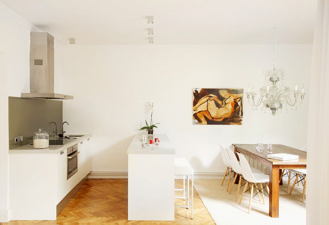 Designerküche in Weiß und Essbereich mit Holztisch und Eames Stühlen