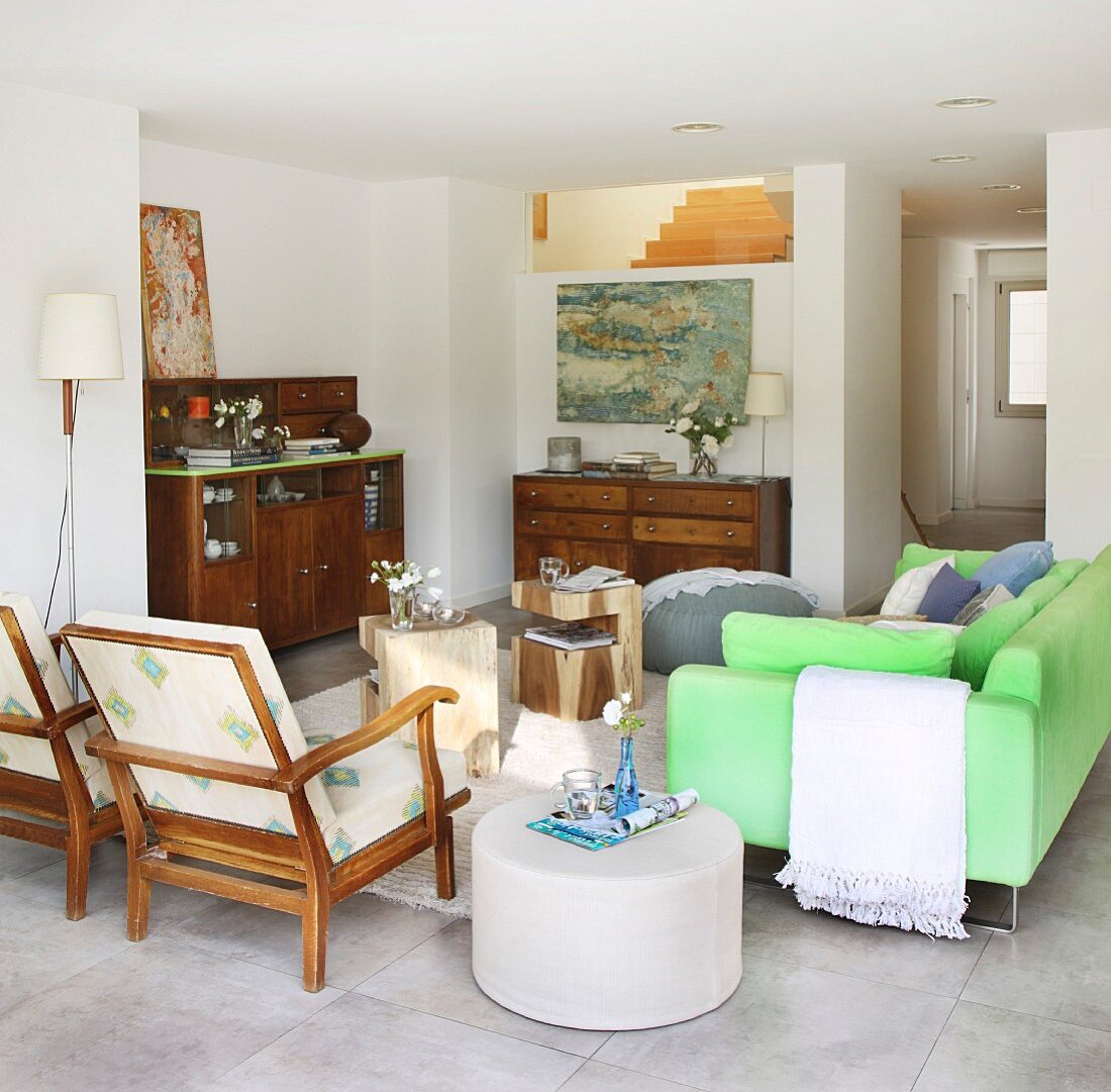 Offener Wohnbereich mit neongrünem Sofa, Armlehnstüheln und Antikmöbeln