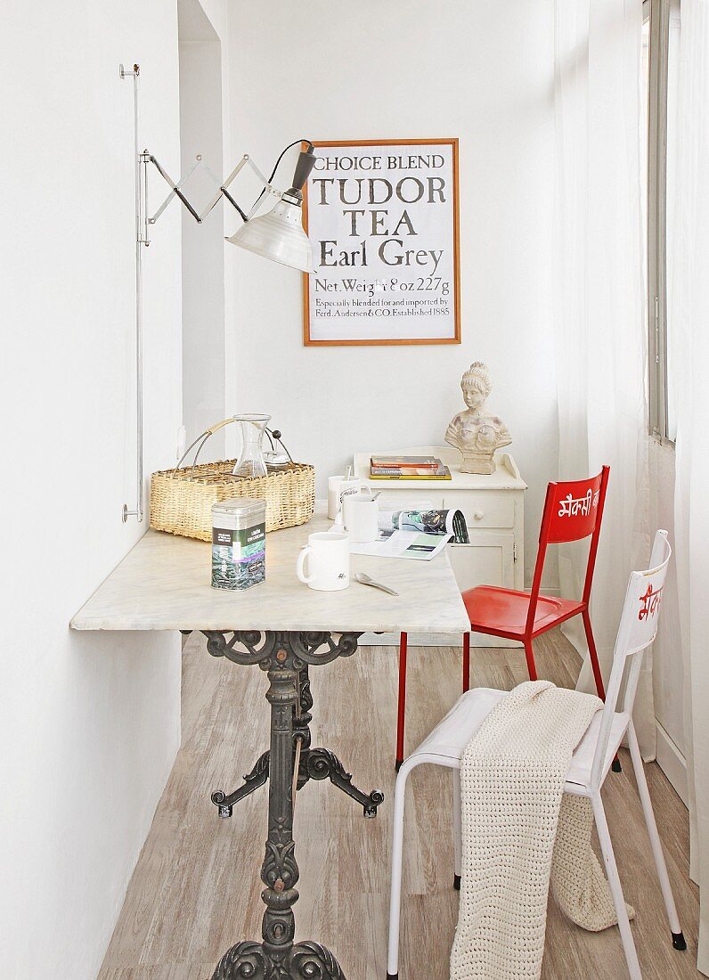 Bistrotisch mit Marmorplatte und gusseisernem Tischgestell in schmalem Zimmer mit zwei Stühlen