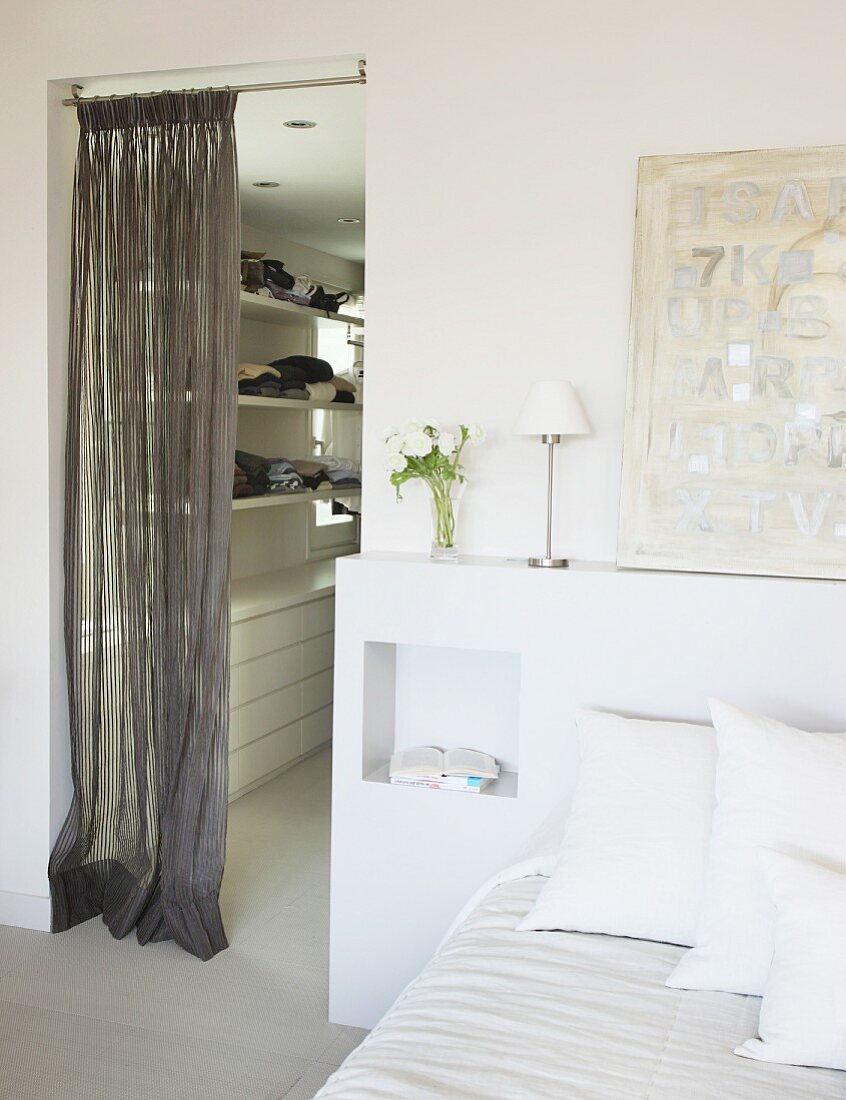 Doppelbett mit weißem Regal am Bettende, neben Durchgang zu Ankleidezimmer