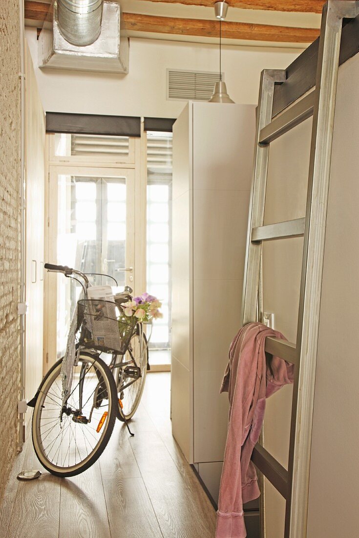 Bettleiter vor Fahrrad im hellen Eingangsbereich von Loftwohnung