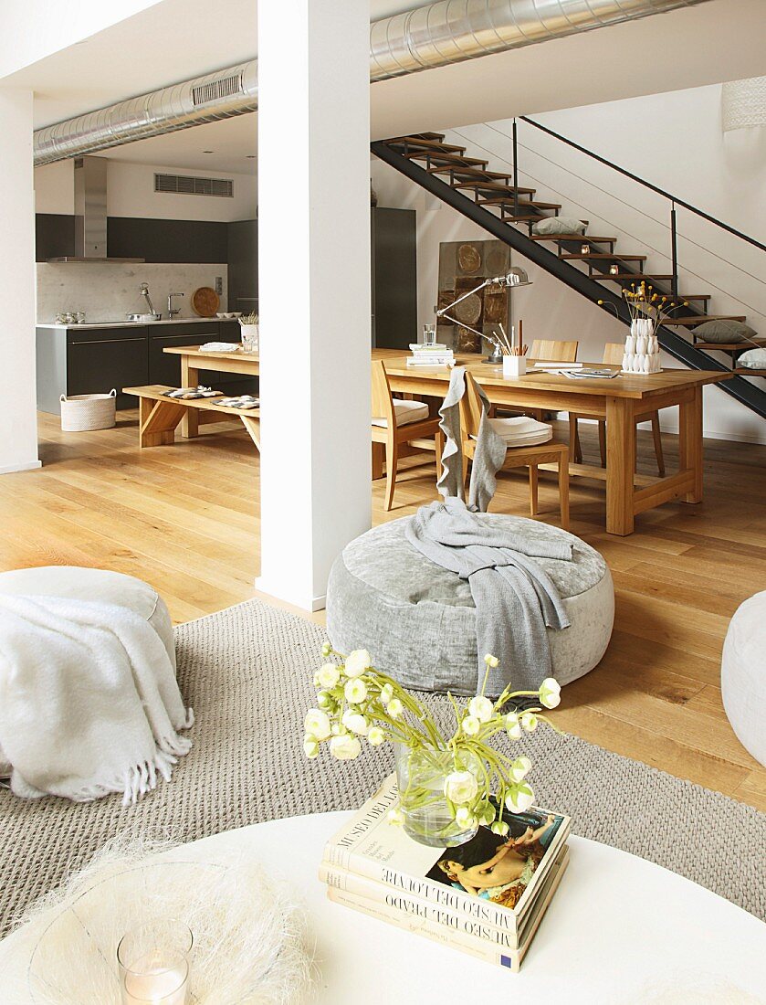Loungebereich vor langem Tisch und Küchenzeile in Loftwohnung mit Stahltreppe