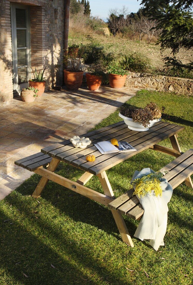 Wooden picnic table and benches in garden outside house