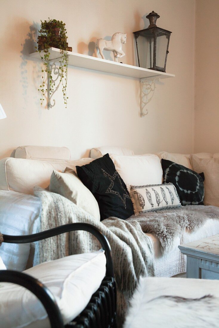 Black and white arrangement of many scatter cushions, fur throw and blanket on comfortable sofa