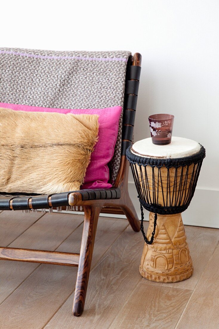 Fur cushion on retro easy chair next to drum