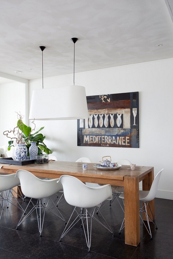 Wooden table and white, modern shell chairs in dining room